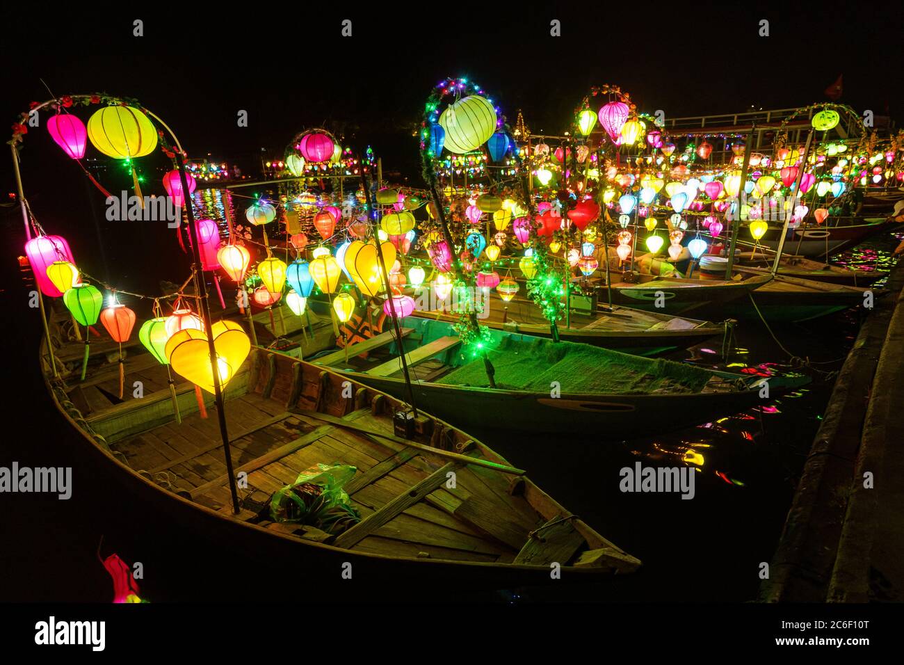 Asiatisches Boot mit farbigen chinesischen Laternen, die nachts im Wasser sein Licht reflektieren Stockfoto