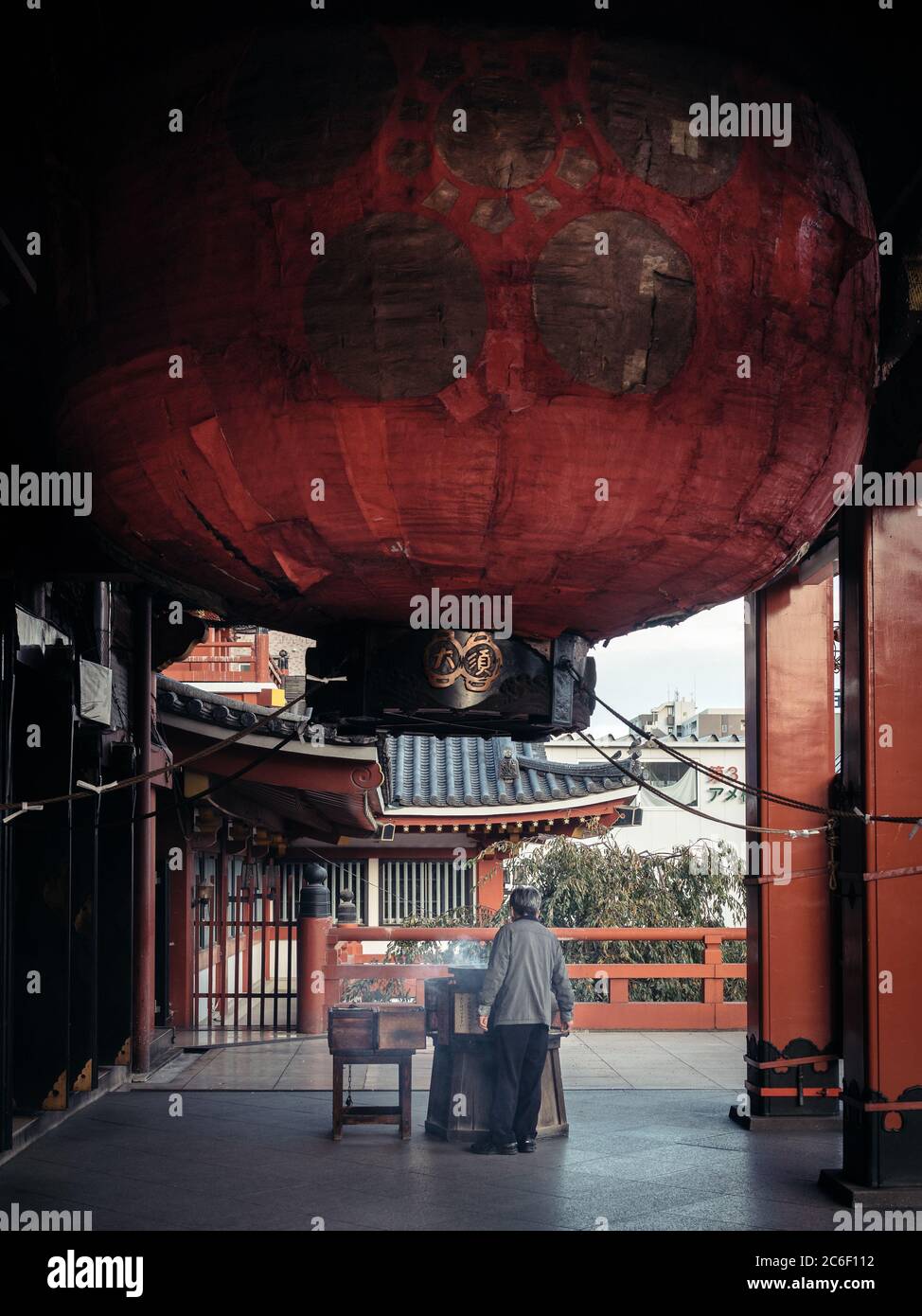 Nagoya, Aichi, Japan - ein alter Mann, der eine Kultfeier unter der riesigen roten japanischen Laterne in Osu Kannon hat. Buddhistischer Tempel in Ōsu. Stockfoto