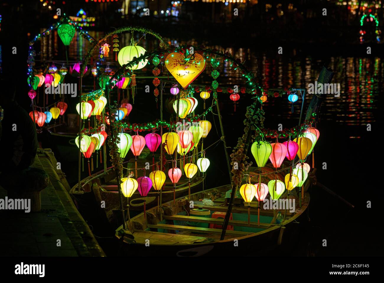 Asiatisches Boot mit farbigen chinesischen Laternen, die nachts im Wasser sein Licht reflektieren Stockfoto
