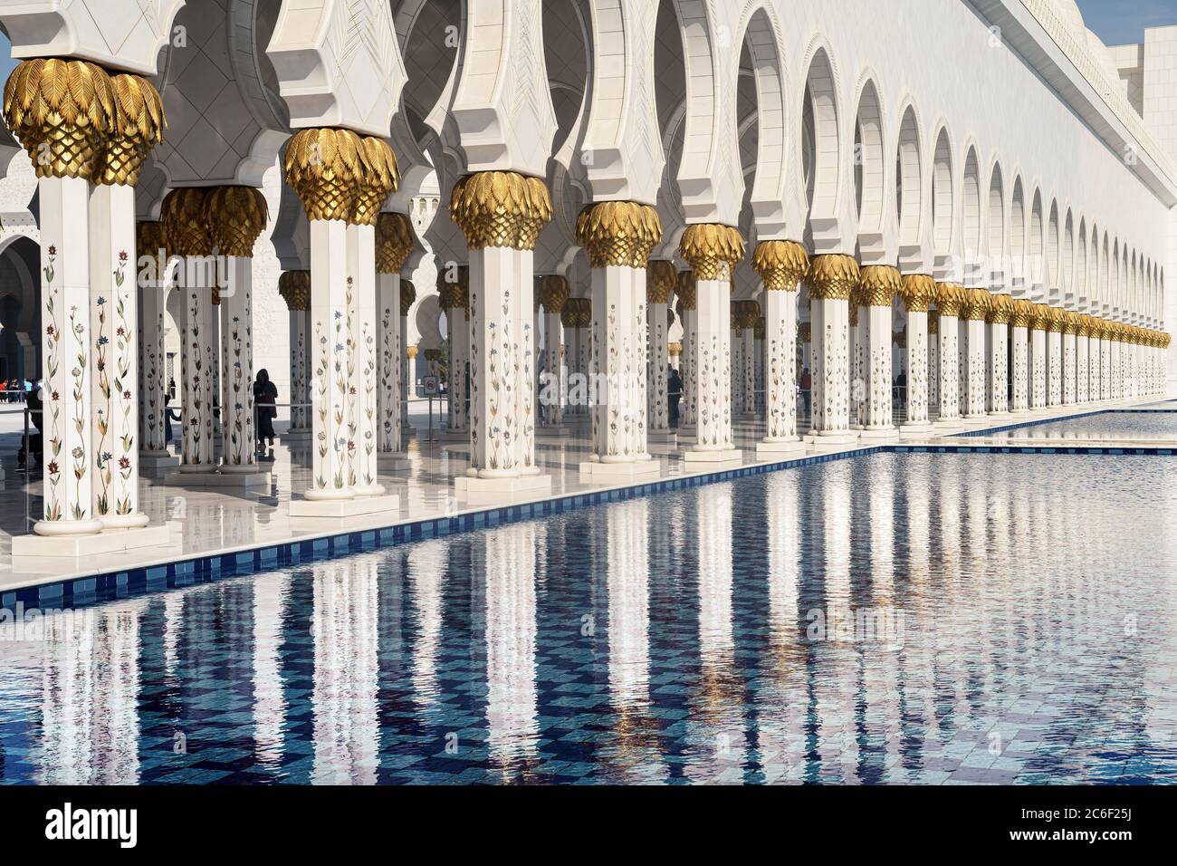 Blick auf die weißen Säulen der Abu Dhabi Moschee, die sich an einem sonnigen Tag im Wasser des Pools spiegeln. Stockfoto