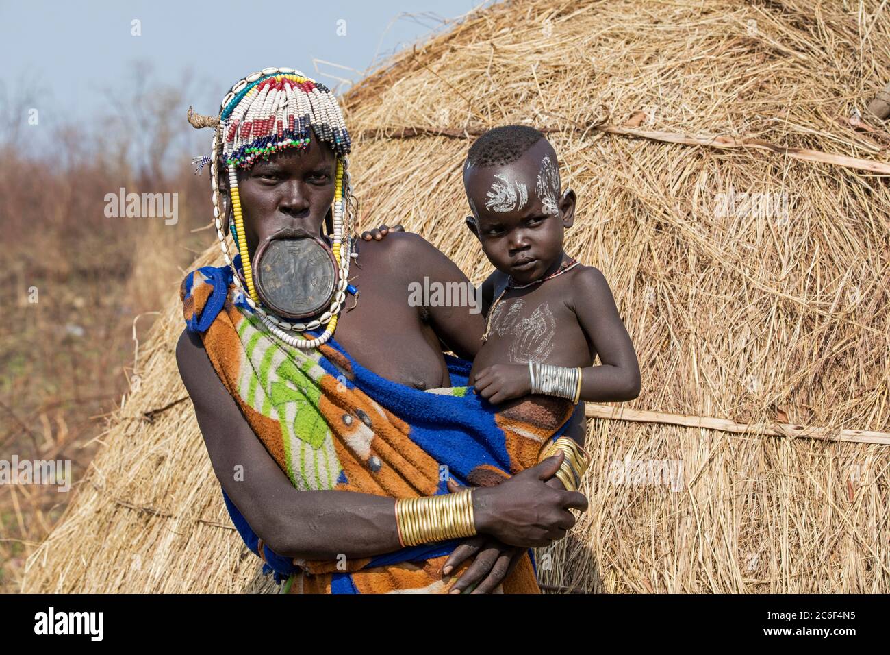 Schwarze Frau mit Kind des Mursi Stammes trägt Lippenplatte und Perlen im Mago Nationalpark in der Nähe von Jinka, Debub Omo Zone, Süd-Äthiopien, Afrika Stockfoto