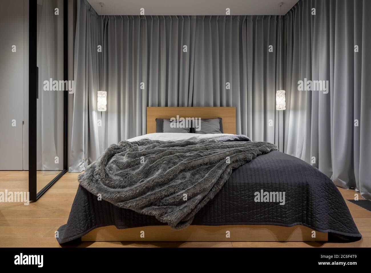 Luxuriöses Schlafzimmer mit Doppelbett und dekorativen grauen Vorhängen Stockfoto