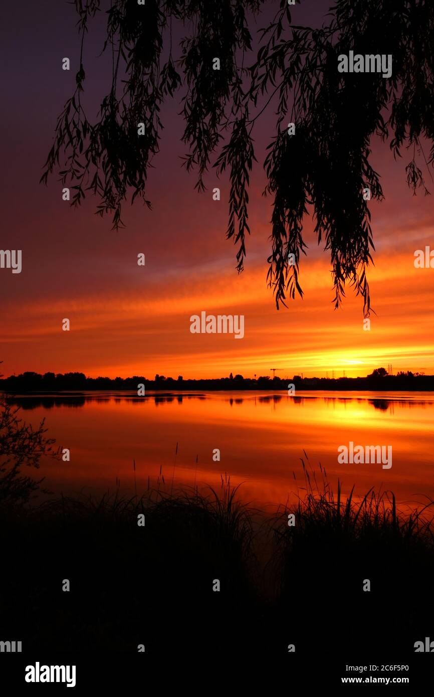 Symmetrie des Himmels in einem See bei Sonnenaufgang. Wolken, die sich auf dem Wasser spiegeln. Ferienlandschaft am Meer. Ruhige entspannende Szene mit einem schönen bunten Stockfoto