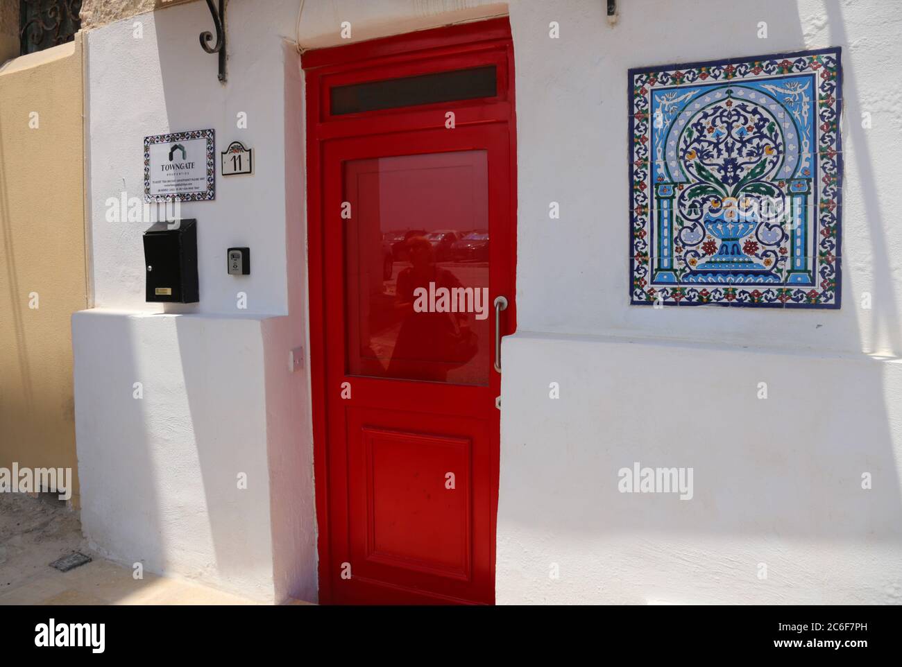 Valletta. Malta. Altstadt. Rote Tür und Keramikfliesen mit arabischem Motiv an der Vorderwand. Stockfoto