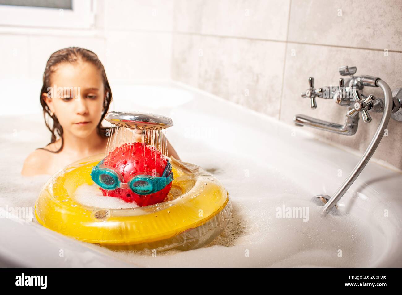 Lustige kleine unidentifizierte Mädchen Duschen einen Kopf aus einem Ball  und Schwimmbrille aus der Dusche, während das Bad zu Hause baden. Konzept  von Stockfotografie - Alamy