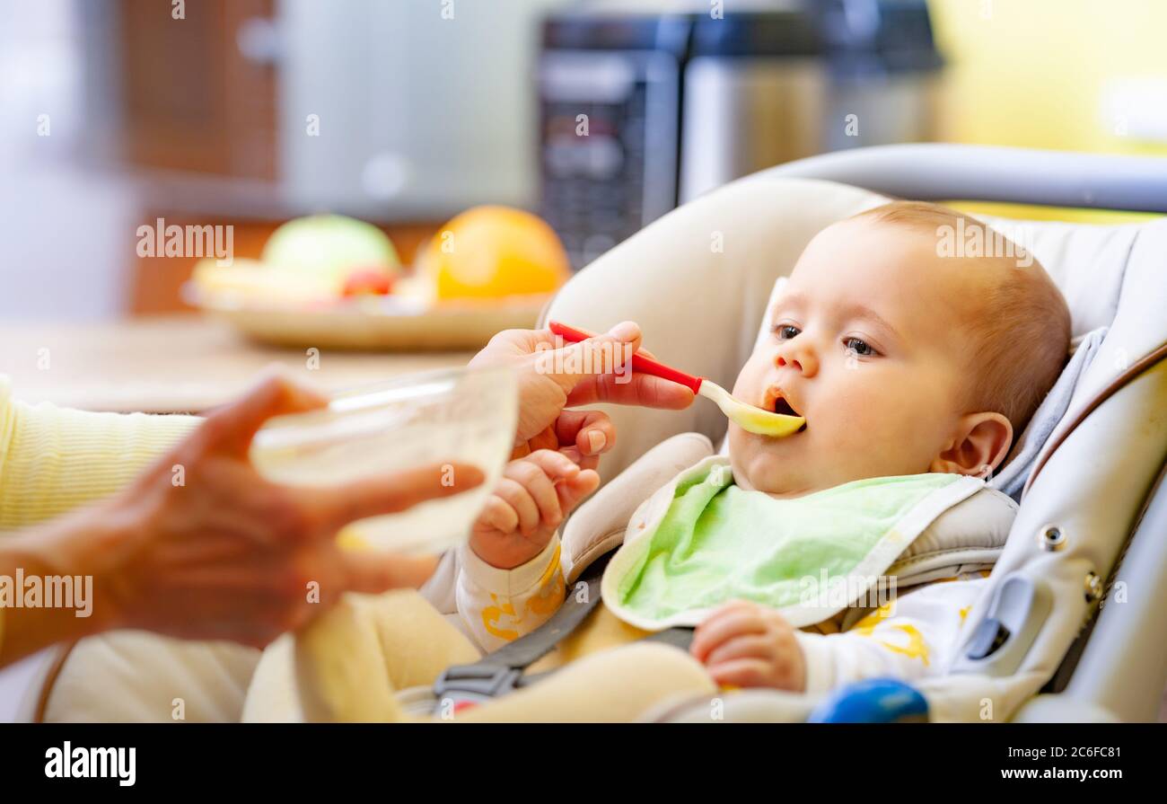 Seitenansicht eines intelligenten kleinen Mädchens Kleinkind sitzt in einem Kindersitz und knabbert ein Spielzeug, während Sie auf Mutter. Das Konzept der richtigen emotionalen Entwicklung Stockfoto