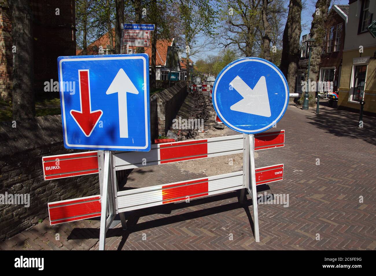 Gebrochene Straße im niederländischen Dorf Bergen, mit Verkehrsschildern, die anzeigen, wer Wegrecht hat und auf welcher Seite Sie passieren müssen. Stockfoto