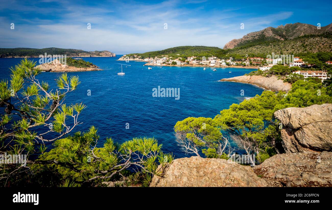 Malerischer Anblick durch Pinienzweige über die Bucht von sant Ulm mit Booten in der Mitte, die Insel sa dragonera auf der linken Seite und Berge Stockfoto