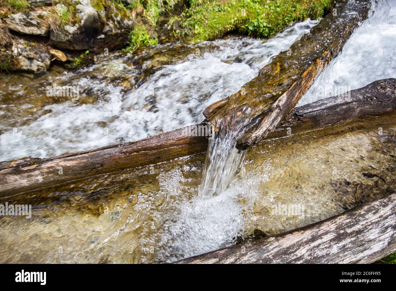 Natur sumping Wasser fließen aus dem Berg durch eine alte moosige Holzröhre Stockfoto