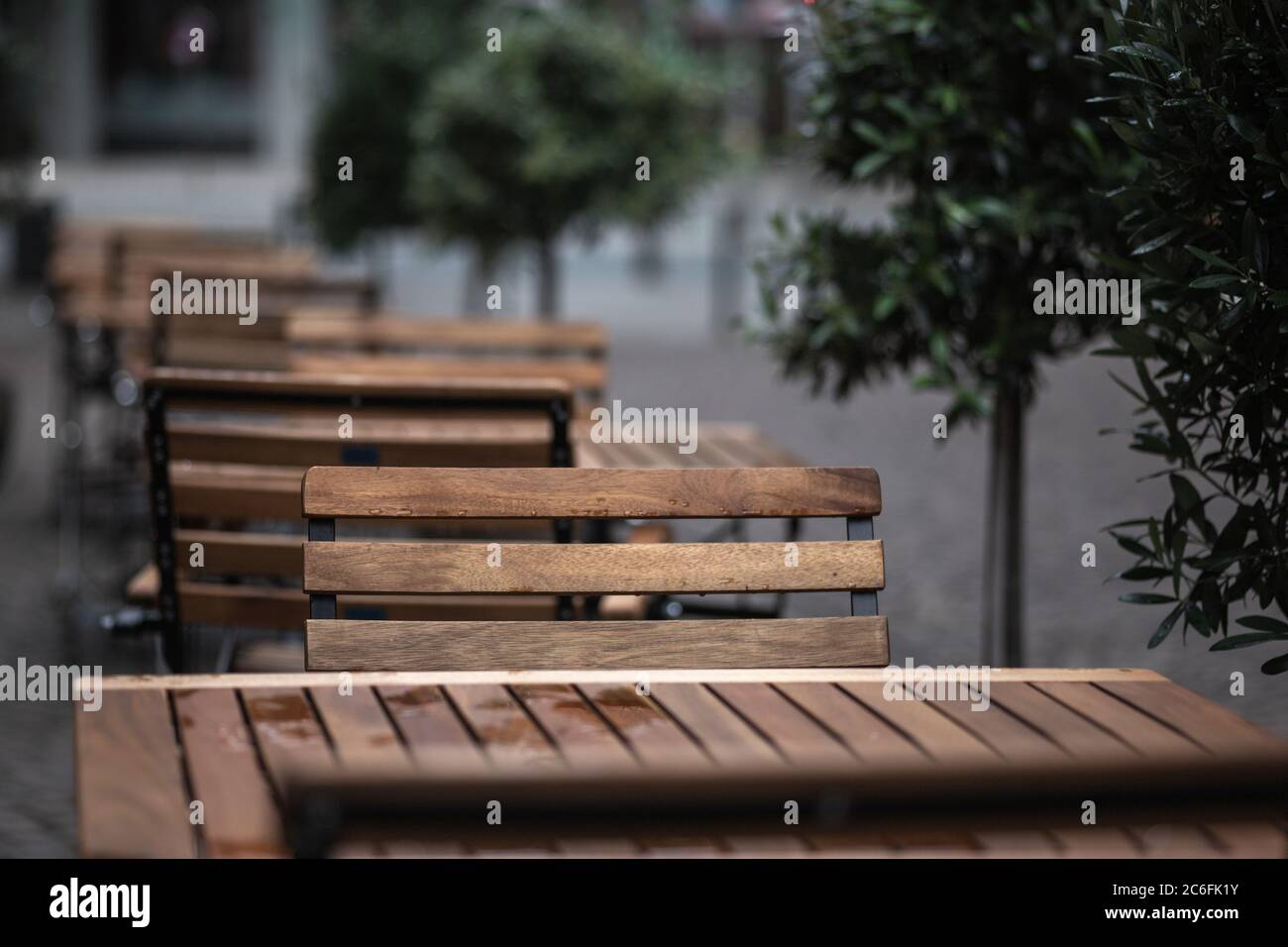 Leere Stühle und Tische mit Regentropfen vor einem Restaurant während der Corona-Sperre Stockfoto