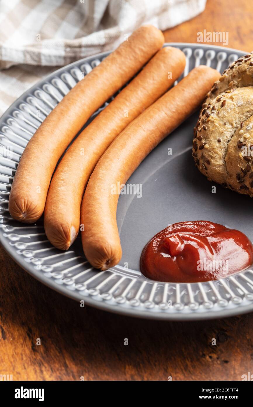 Frische frankfurter Würstchen mit Brötchen und Ketchup auf dem Teller. Stockfoto