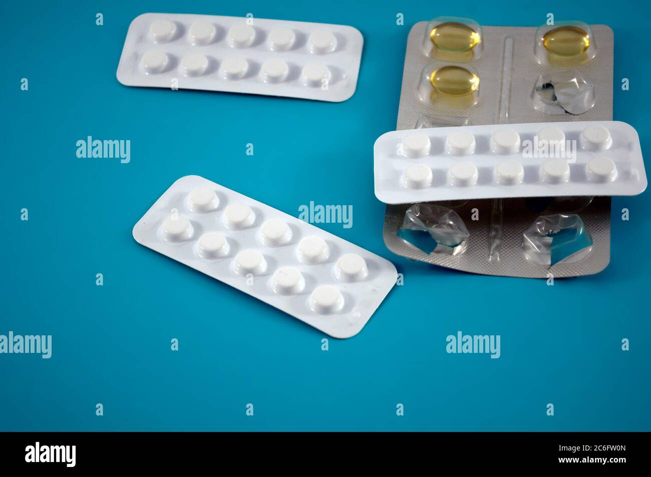 Blister von weißen und gelben Pillen, Vitamine, Tablette, Medizin auf grünem Hintergrund Stockfoto