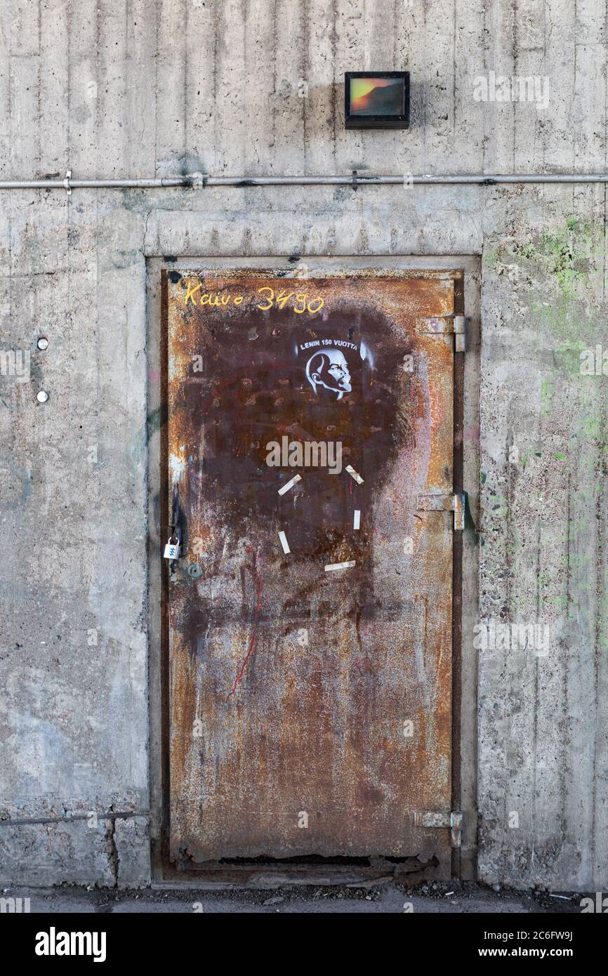 Verrostete alte Tür mit Lenin-Schablonen-Graffiti unter der Hakaniemi-Brücke in Helsinki, Finnland Stockfoto