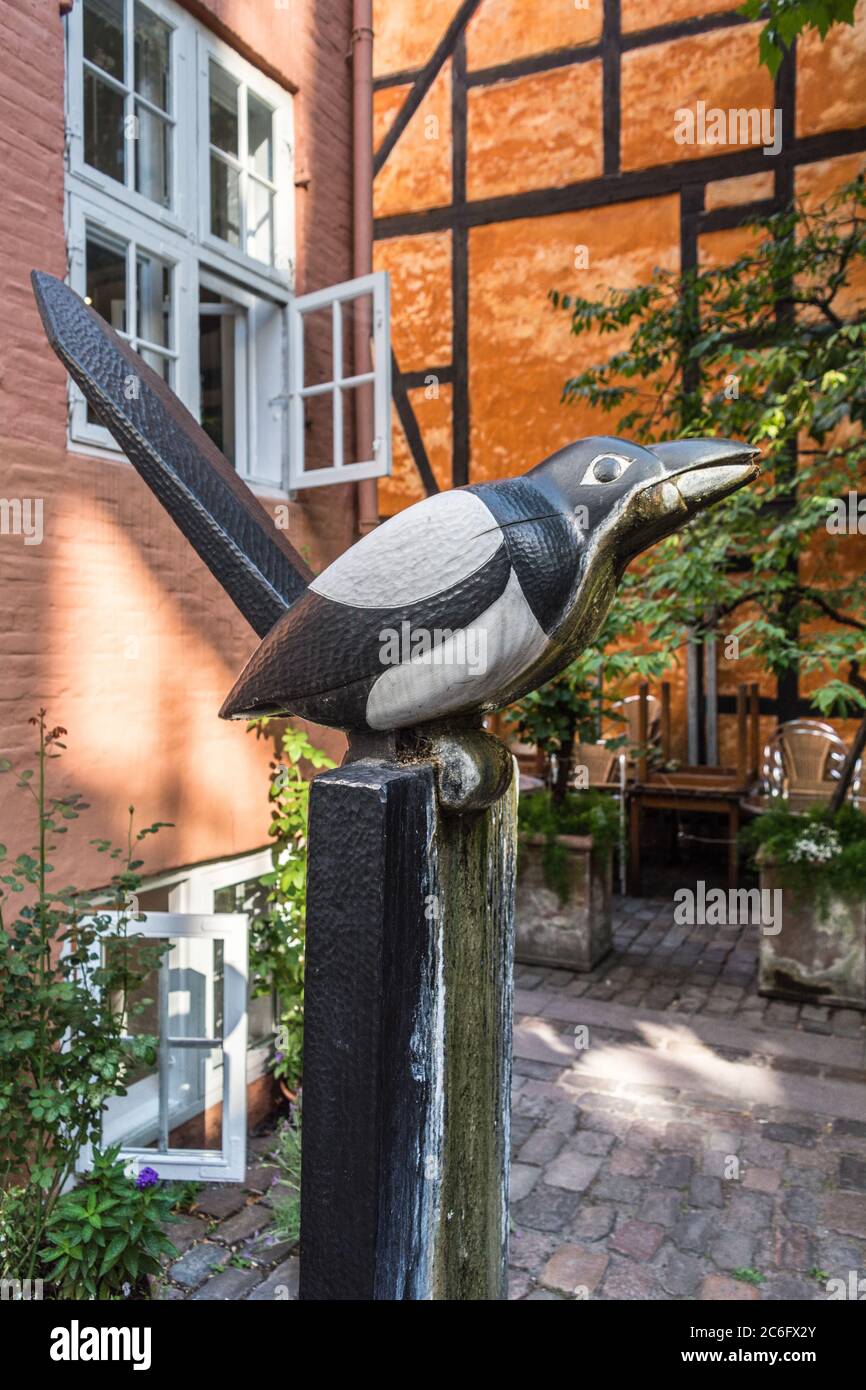 Eine Elster-Gartenskulptur befindet sich neben einem Fachwerkhaus in Kopenhagen, Dänemark Stockfoto