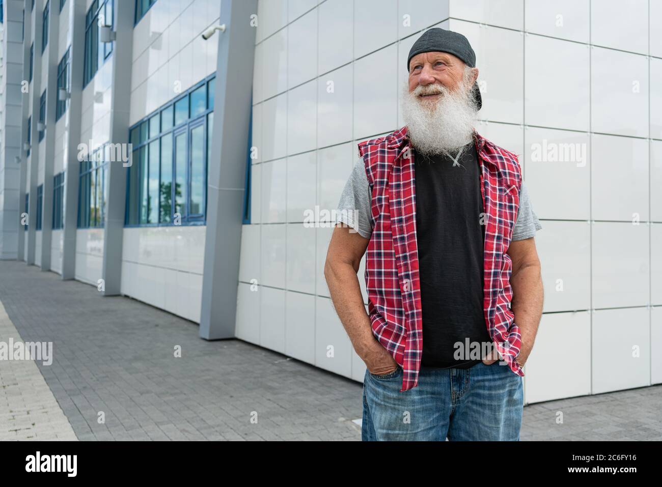 Erfahrener älterer Mann mit Bart auf der Straße posiert und lächelt, Porträt Stockfoto