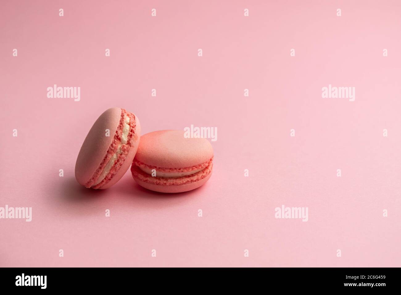Französische rosa Makronen auf hellrosa Hintergrund, monochromer Hintergrund Stockfoto