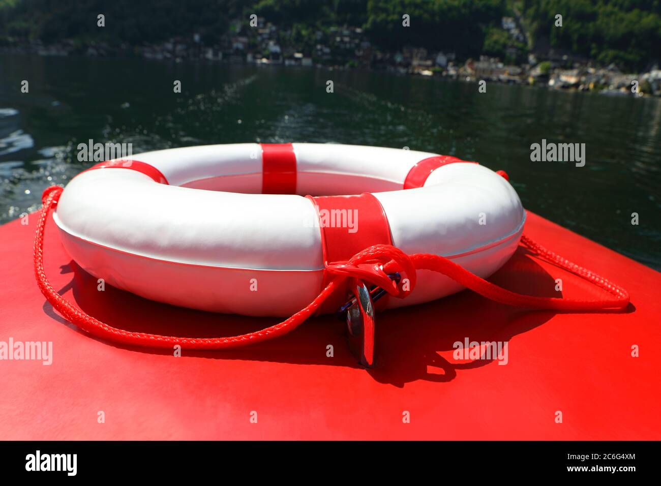 Sicherheitsschild, Rettungsring auf dem roten Boot im grünen Seenwasser Stockfoto