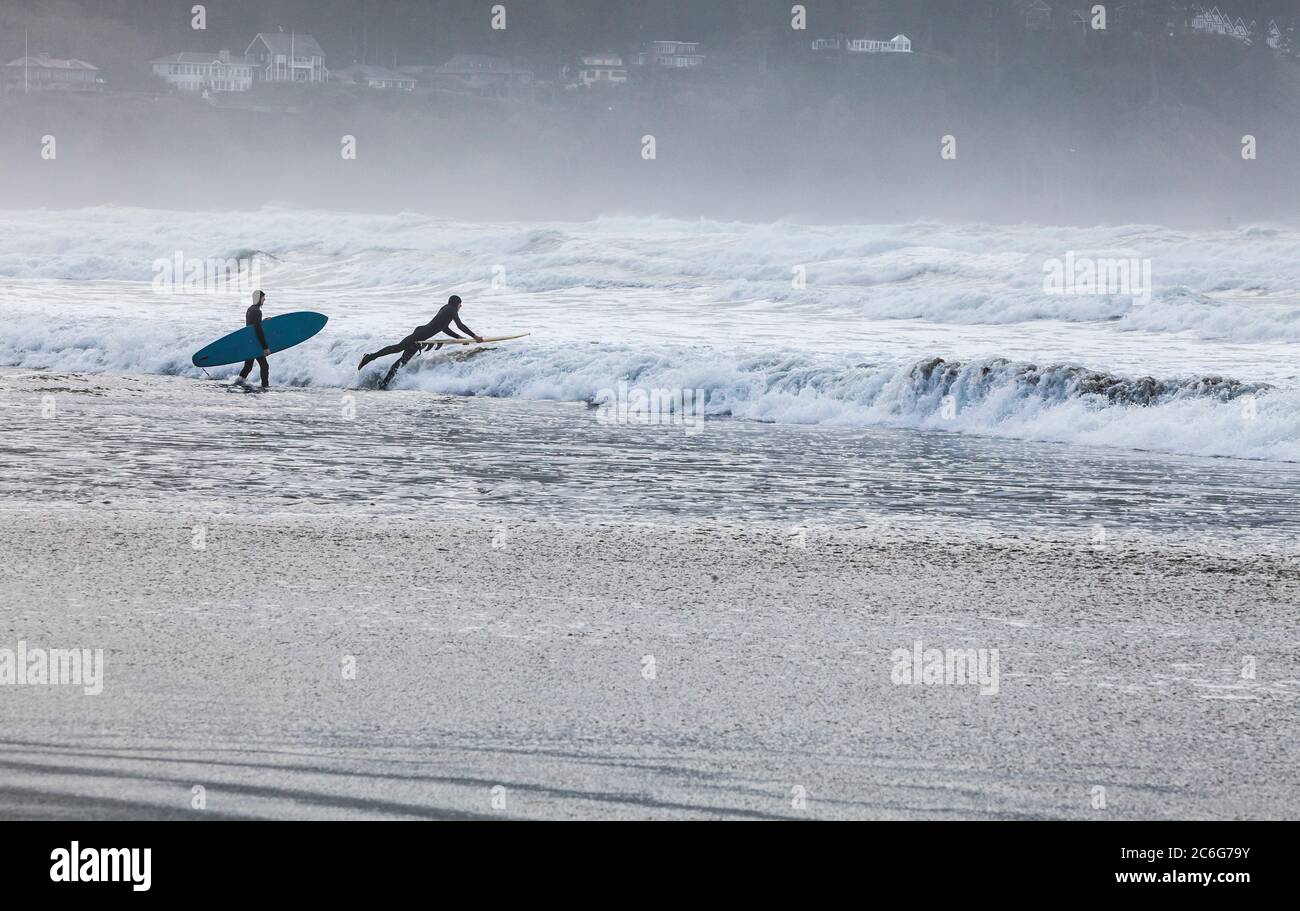 Zwei junge Männer gingen mit Surfbrettern in die Suf. Pazifikküste, Küste, Oregon, USA. Stockfoto
