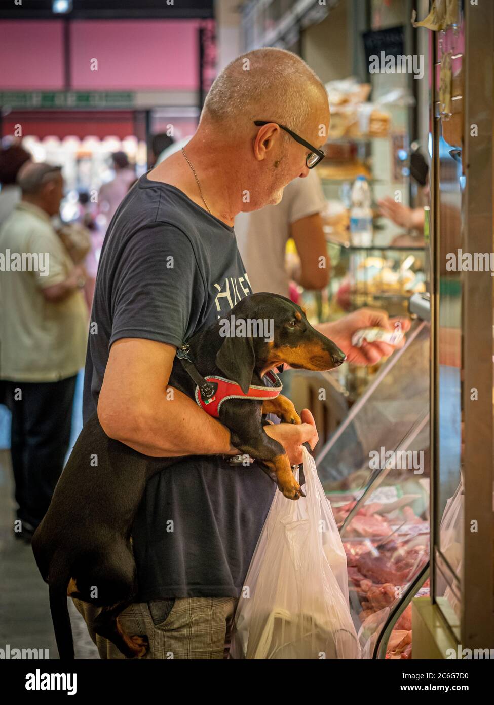 Mann mit einem Dachshund-Hund beim Blick auf Fleisch auf Mercato Albinelli, Modena, Italien. Stockfoto