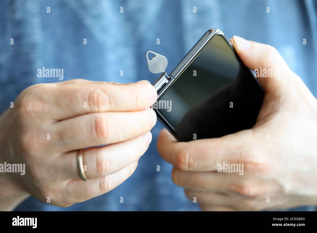 Man zieht SIM-Kartensteckplatz für neues Telefon mit Stift heraus Stockfoto