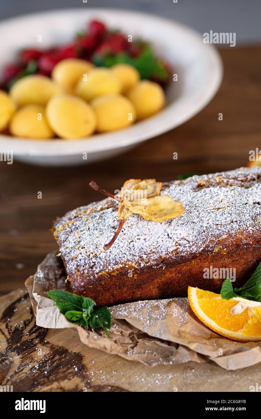 Kuchen ist mit getrockneten Früchten, Orange und Minze dekoriert, daneben ist Teller mit Aprikosen, selektive Fokus, hausgemachte Kuchen in der Küche, Stockfoto