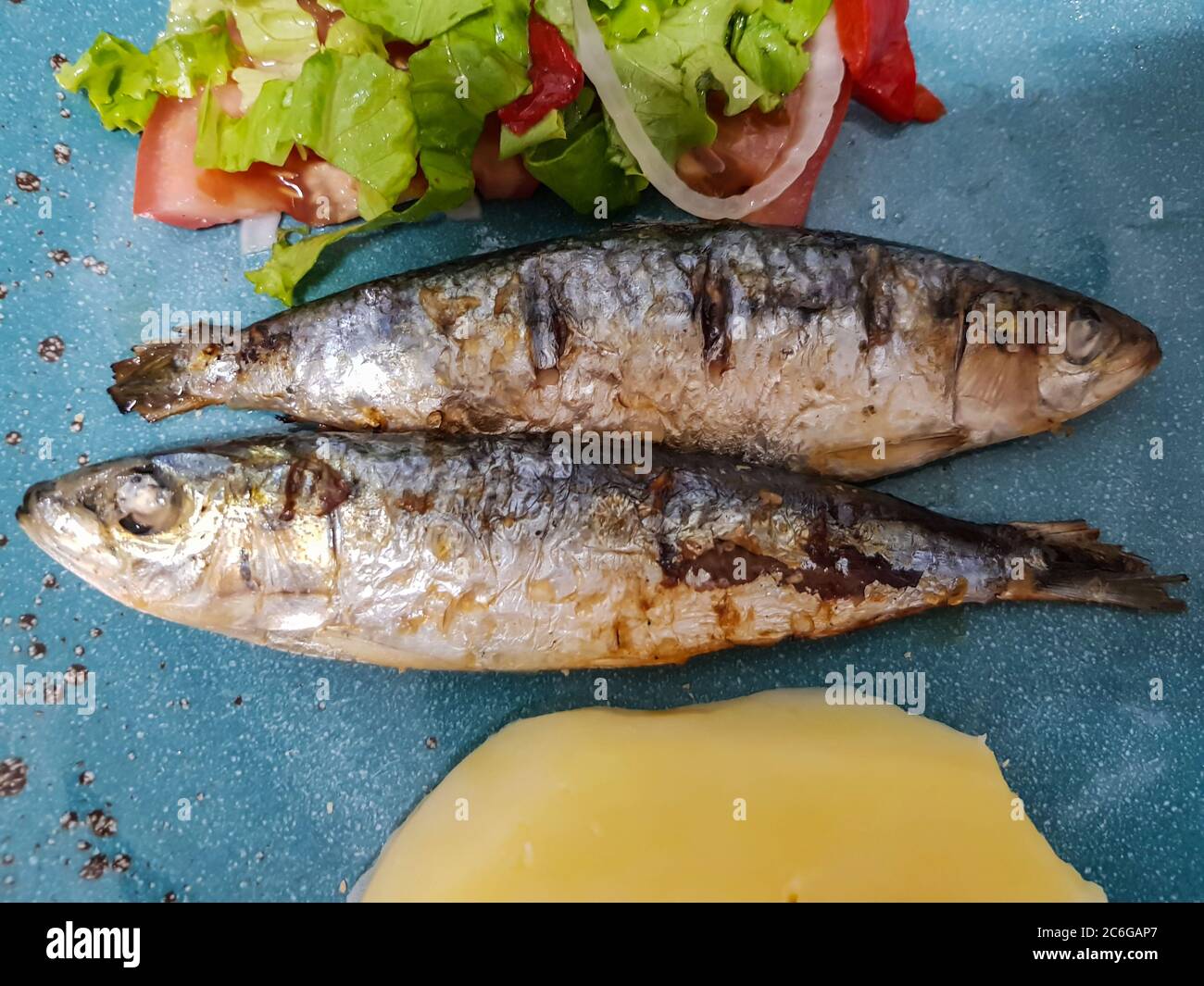 Draufsicht auf geröstete Sardine mit Salat und gekochten Kartoffeln. Typische portugiesische Küche Stockfoto