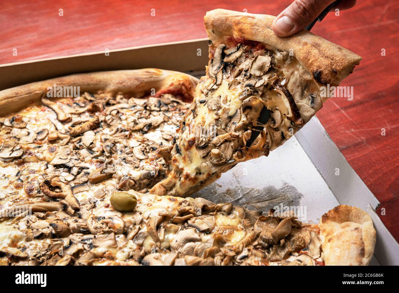 Hand des Mannes nimmt Pizza in einem Karton. Konzept für die Lebensmittelzustellung, Nahaufnahme. Stockfoto