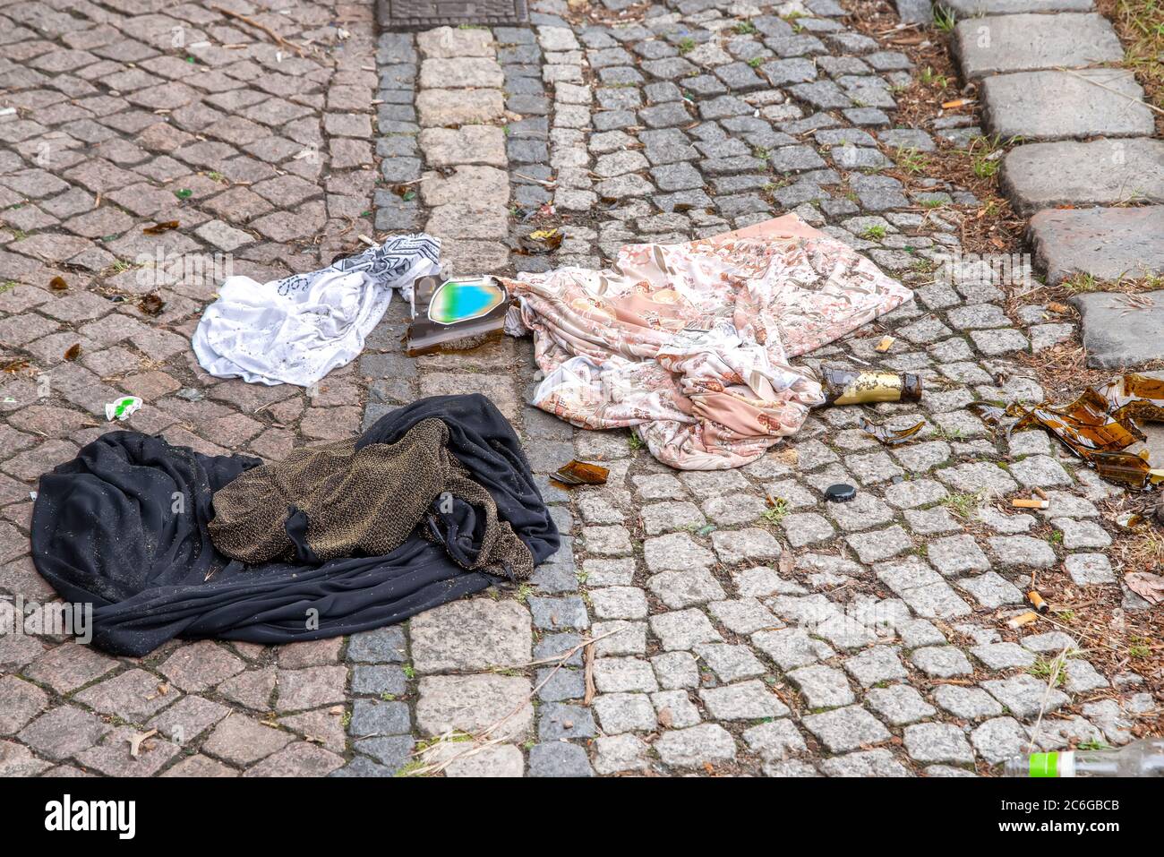 Verschmutzung - Abdeckung, T-Shirt, zerbrochene Bierflasche und Zigarrenbutts achtlos auf der Straße entsorgt. Stockfoto