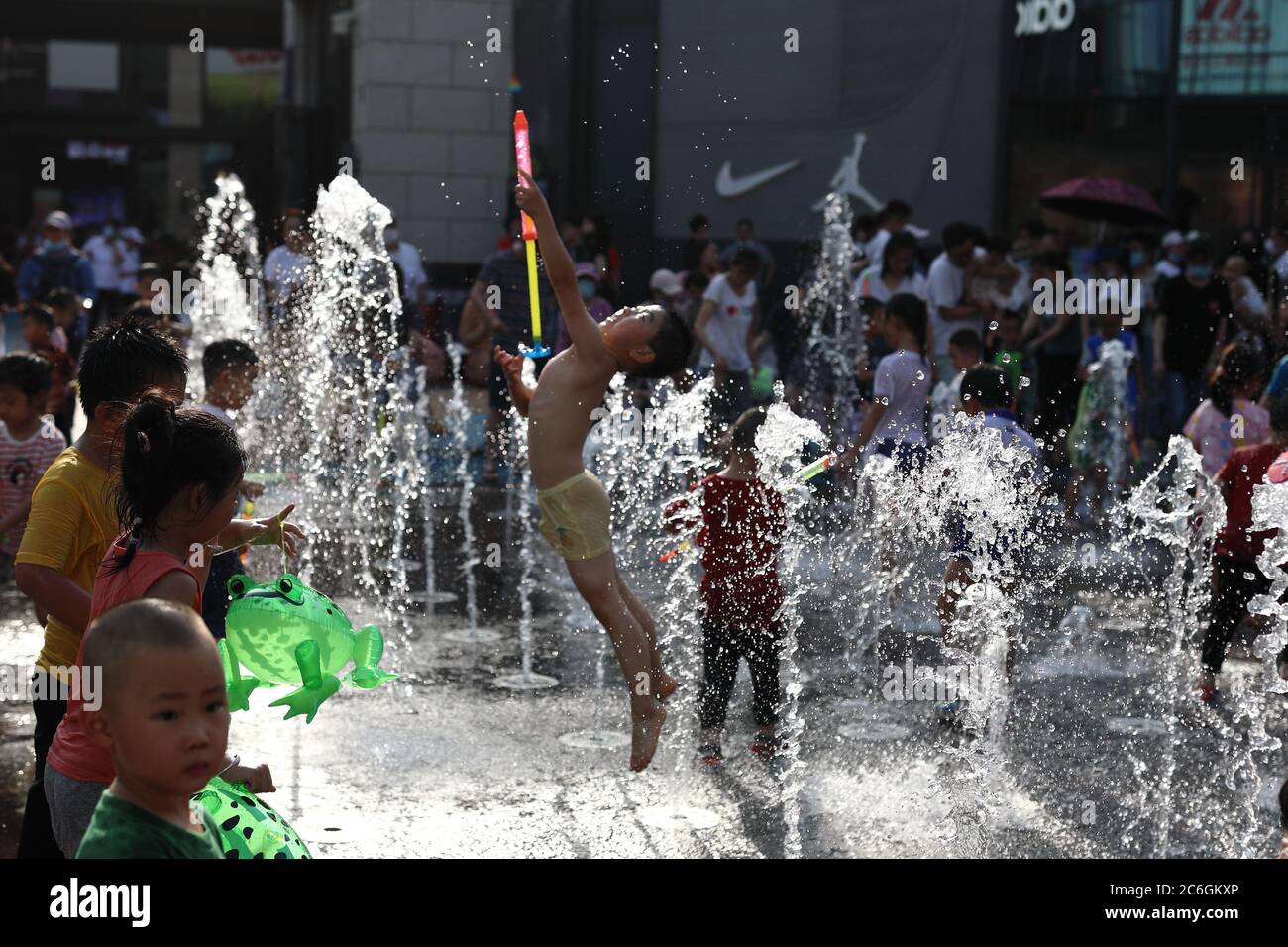 Eine Gruppe von Kindern versammeln sich um einen Brunnen vor einer Mall und spielen Wasser, um die sengende Hitze abzukühlen, Peking, China, 7. Juni 2020. *** Lokale Obergrenze Stockfoto