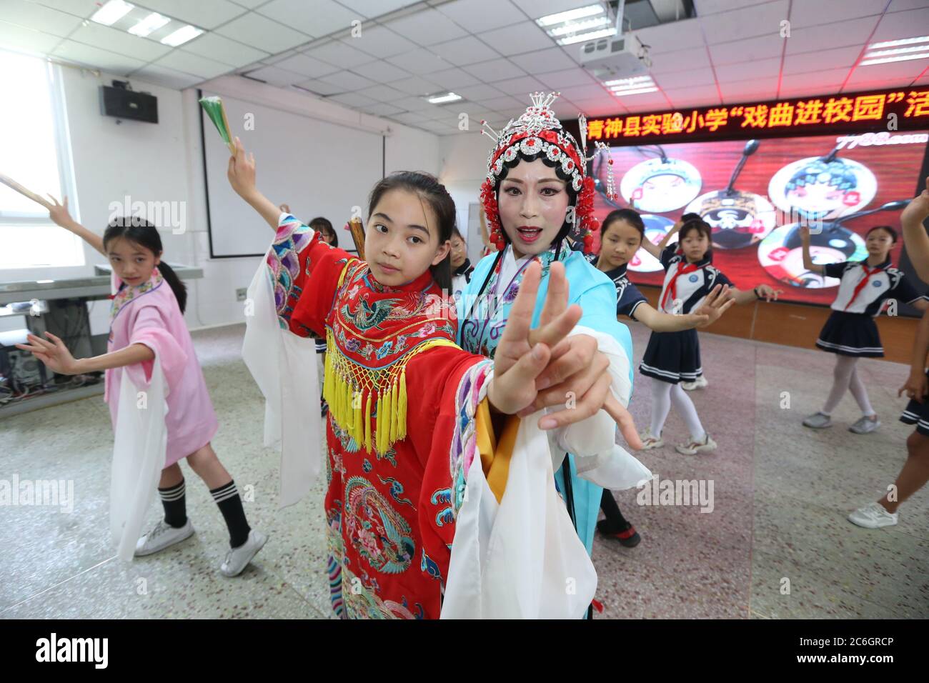Von einer professionellen Schauspielerin der Peking-Oper unterrichtet, erleben lokale Grundschüler, die sich für das immaterielle Kulturerbe interessieren, Oper Stockfoto