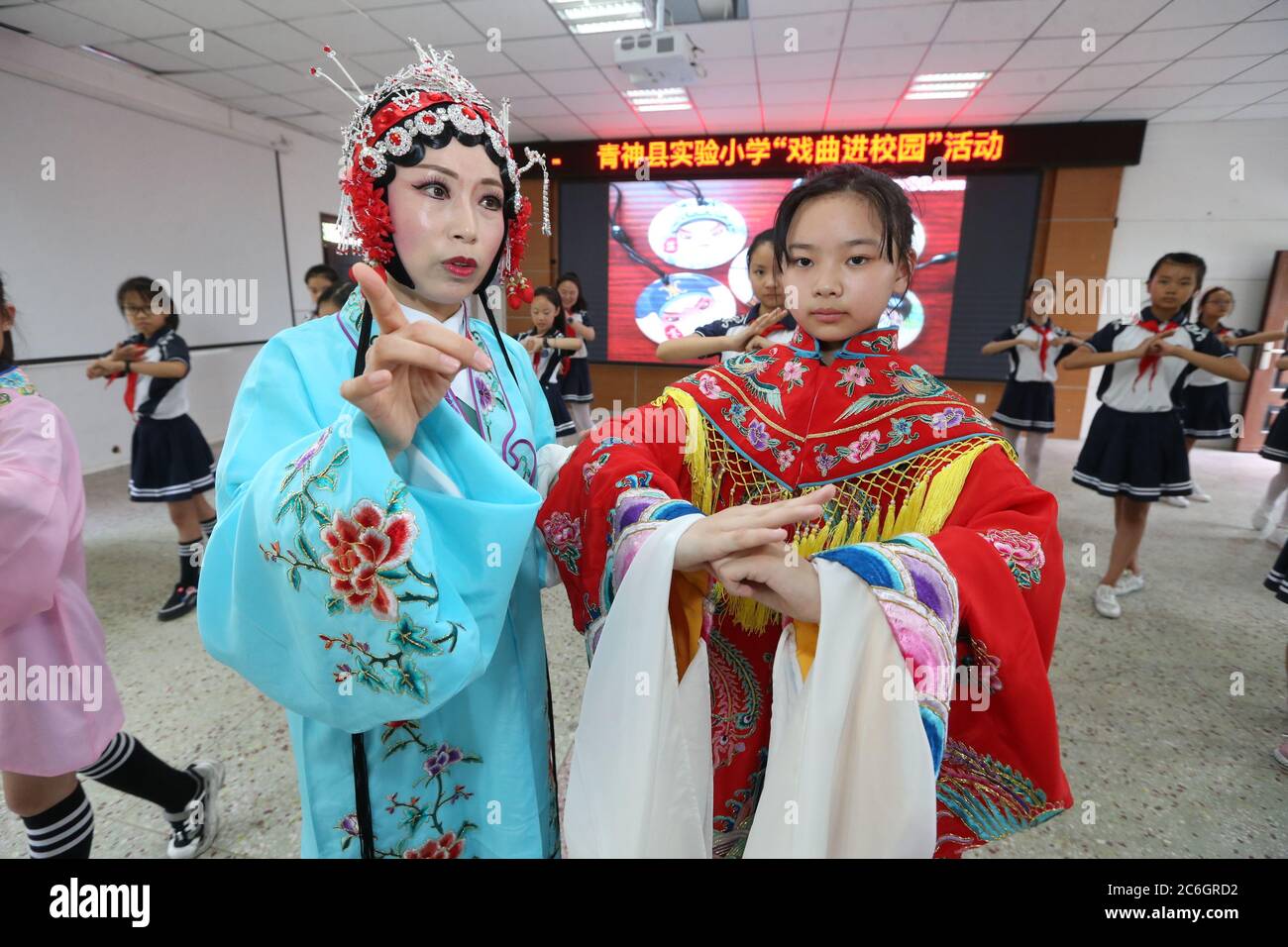 Von einer professionellen Schauspielerin der Peking-Oper unterrichtet, erleben lokale Grundschüler, die sich für das immaterielle Kulturerbe interessieren, Oper Stockfoto