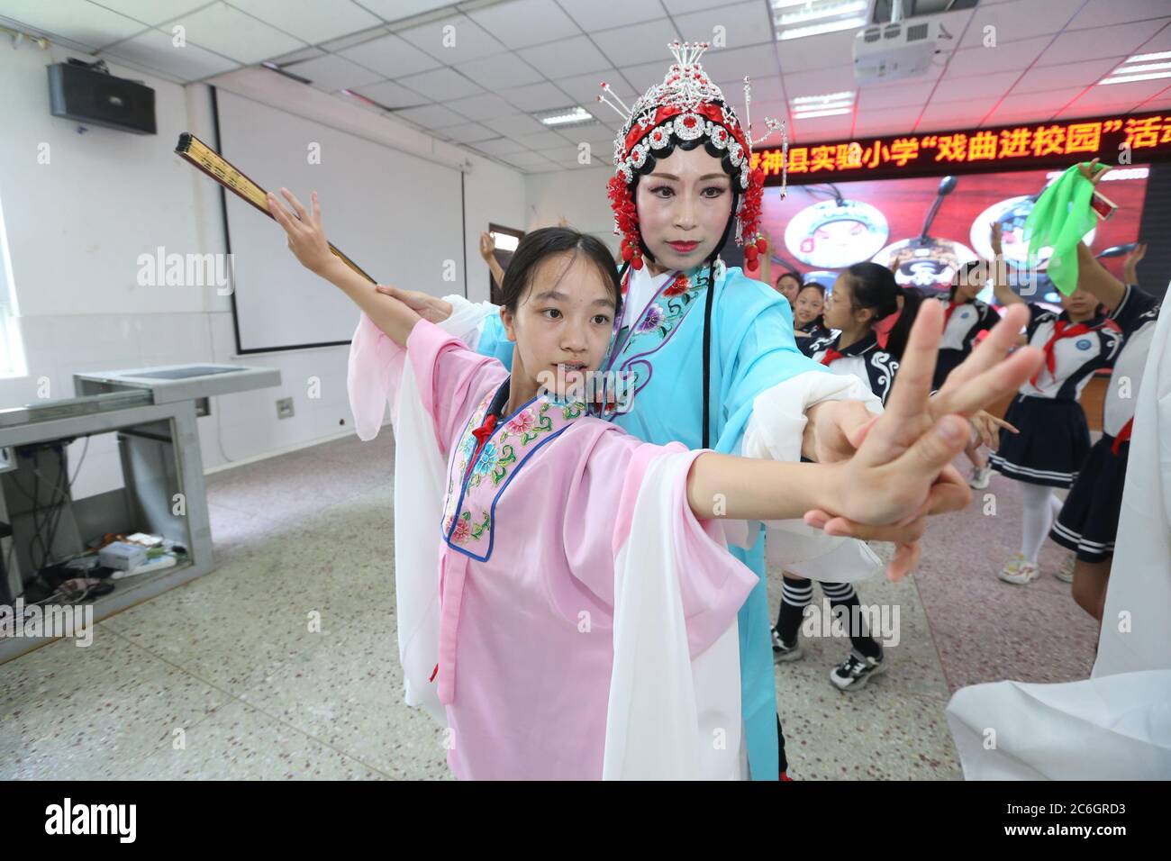 Von einer professionellen Schauspielerin der Peking-Oper unterrichtet, erleben lokale Grundschüler, die sich für das immaterielle Kulturerbe interessieren, Oper Stockfoto