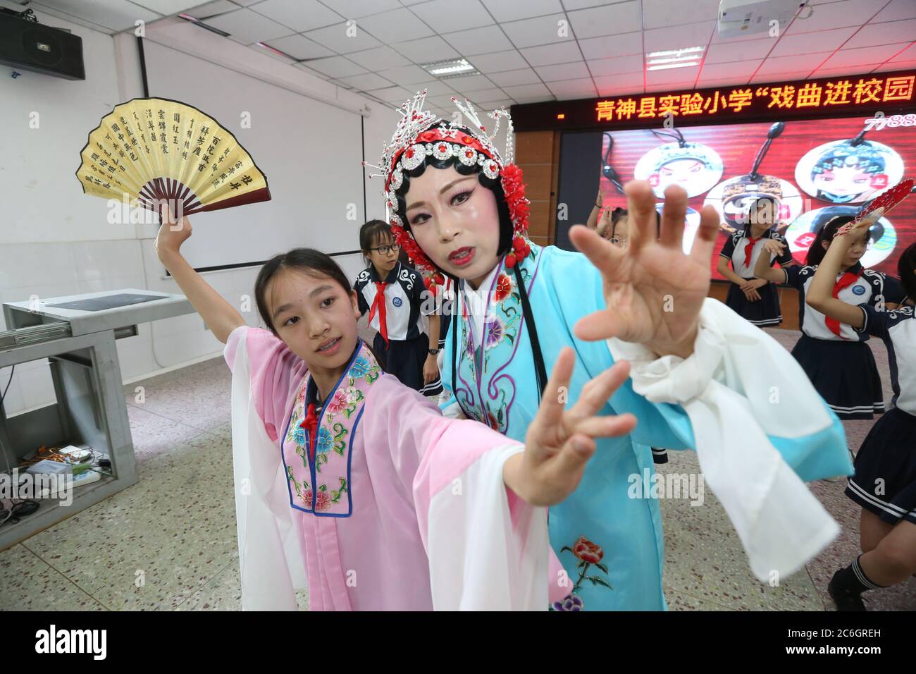 Von einer professionellen Schauspielerin der Peking-Oper unterrichtet, erleben lokale Grundschüler, die sich für das immaterielle Kulturerbe interessieren, Oper Stockfoto