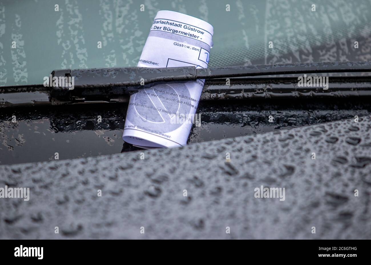 20. Juni 2020, Mecklenburg-Vorpommern, Güstrow: Ein Parkschein steckt unter dem Scheibenwischer eines Autos, das bei Regen am falschen Ort abgestellt wird. Foto: Jens Büttner/dpa-Zentralbild/ZB Stockfoto