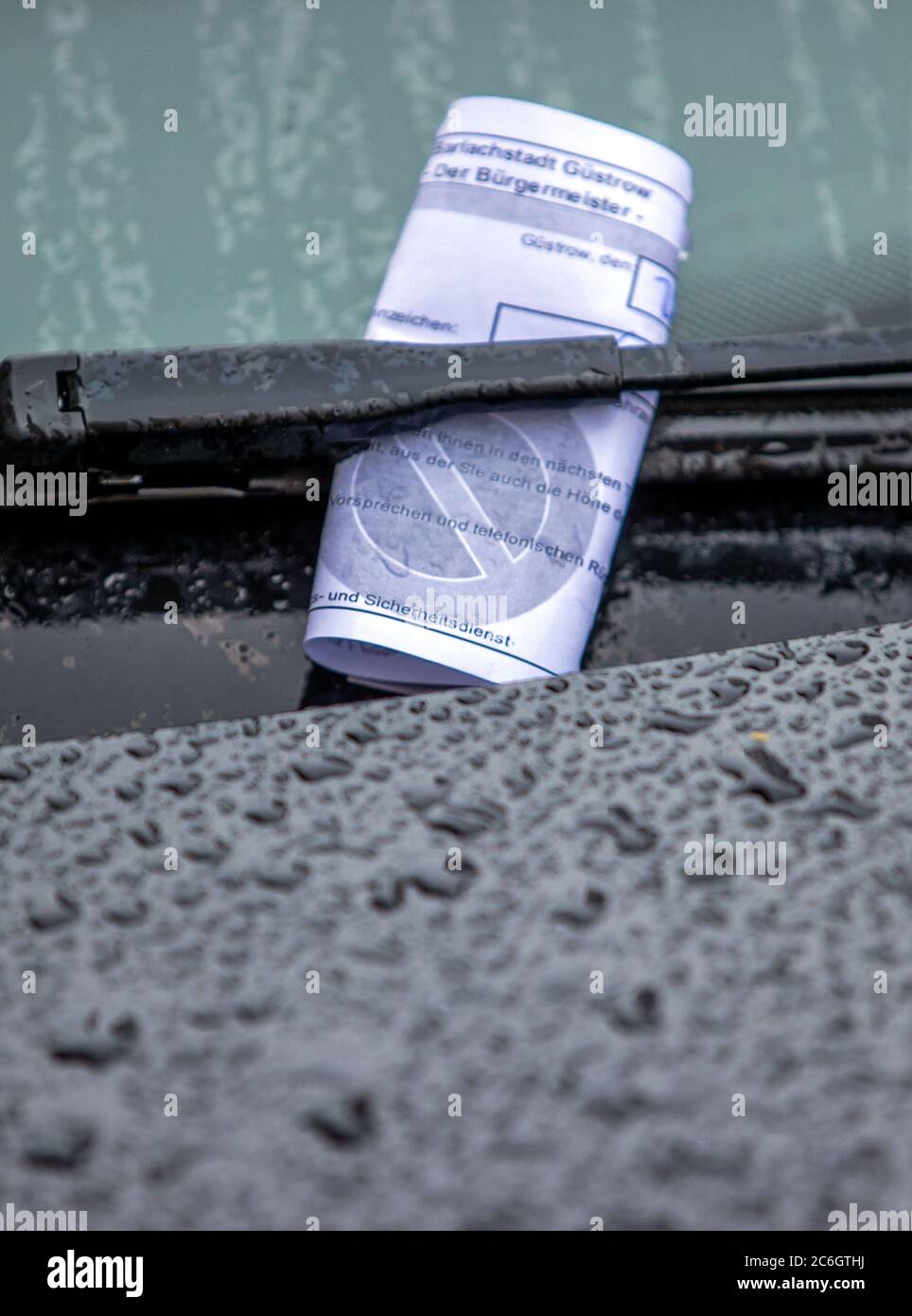 20. Juni 2020, Mecklenburg-Vorpommern, Güstrow: Ein Parkschein steckt unter dem Scheibenwischer eines Autos, das bei Regen am falschen Ort abgestellt wird. Foto: Jens Büttner/dpa-Zentralbild/ZB Stockfoto