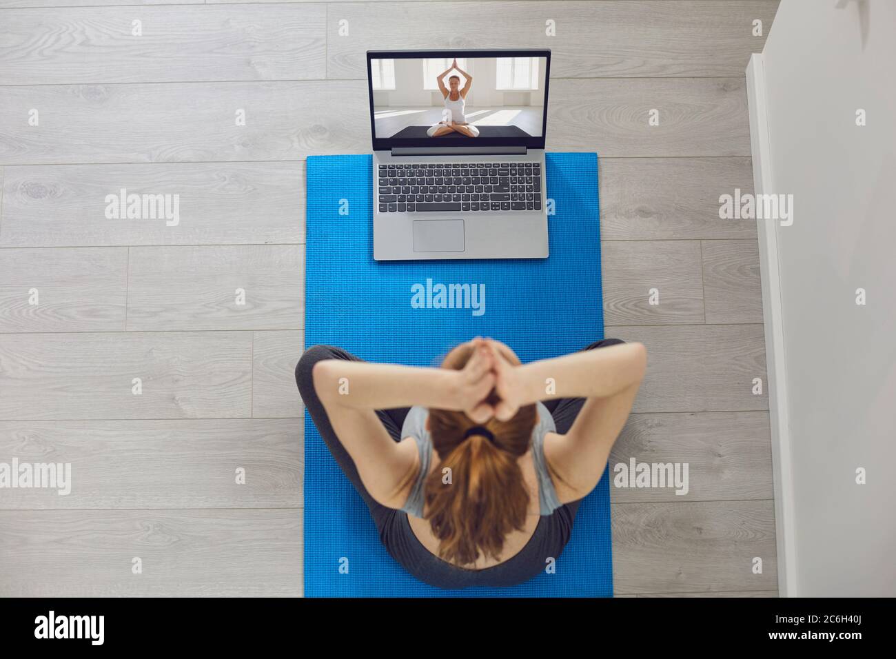 Online-Yoga-Kurs. Mädchen üben Video Anruf Chat Laptop Laptop Yoga Meditation sitzen auf dem Boden drinnen Stockfoto