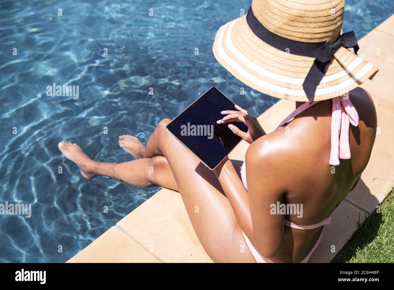 Frau mit digitalen Tablet, während sie am Pool sitzt Stockfoto