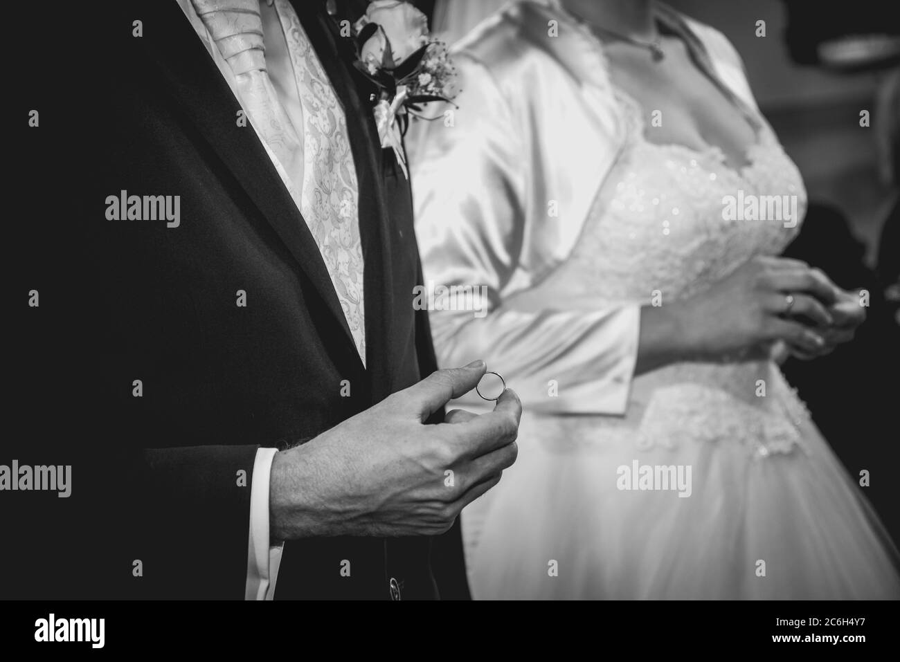 Bräutigam hält den Ehering, bevor er während der Trauung den Finger in die Kirche legt. Schwarzweiß-Foto. Matteffekt Stockfoto