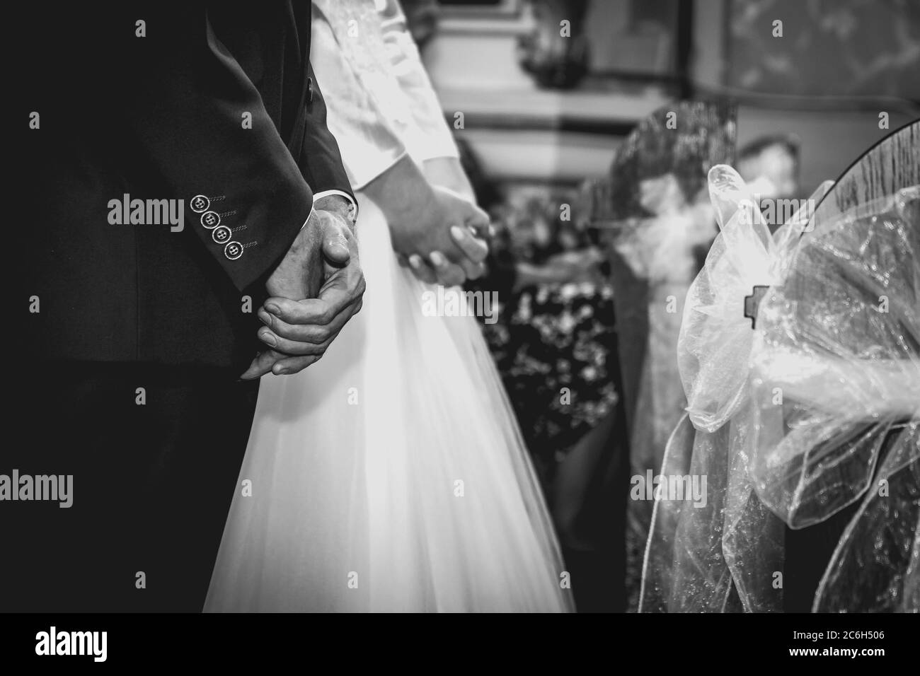 Während der Trauung in der Kirche die Hände des Bräutigams und der Braut aufgeschlagen. Schwarzweißfoto mit Matteffekt Stockfoto
