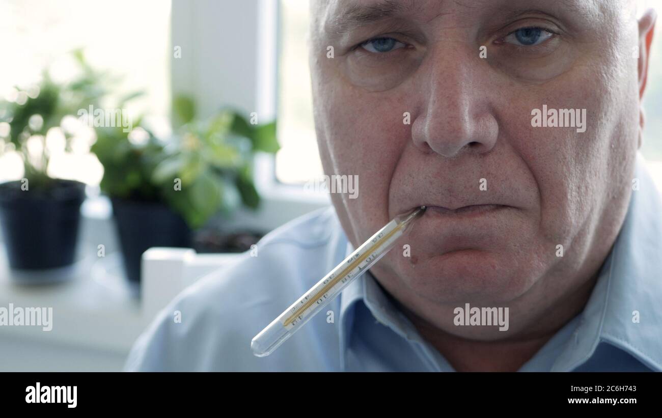 Mann mit Coronavirus-Symptomen, der seine Körpertemperatur in einem Krankenhaus mit einem Thermometer mit Quecksilberskala einnahm Stockfoto