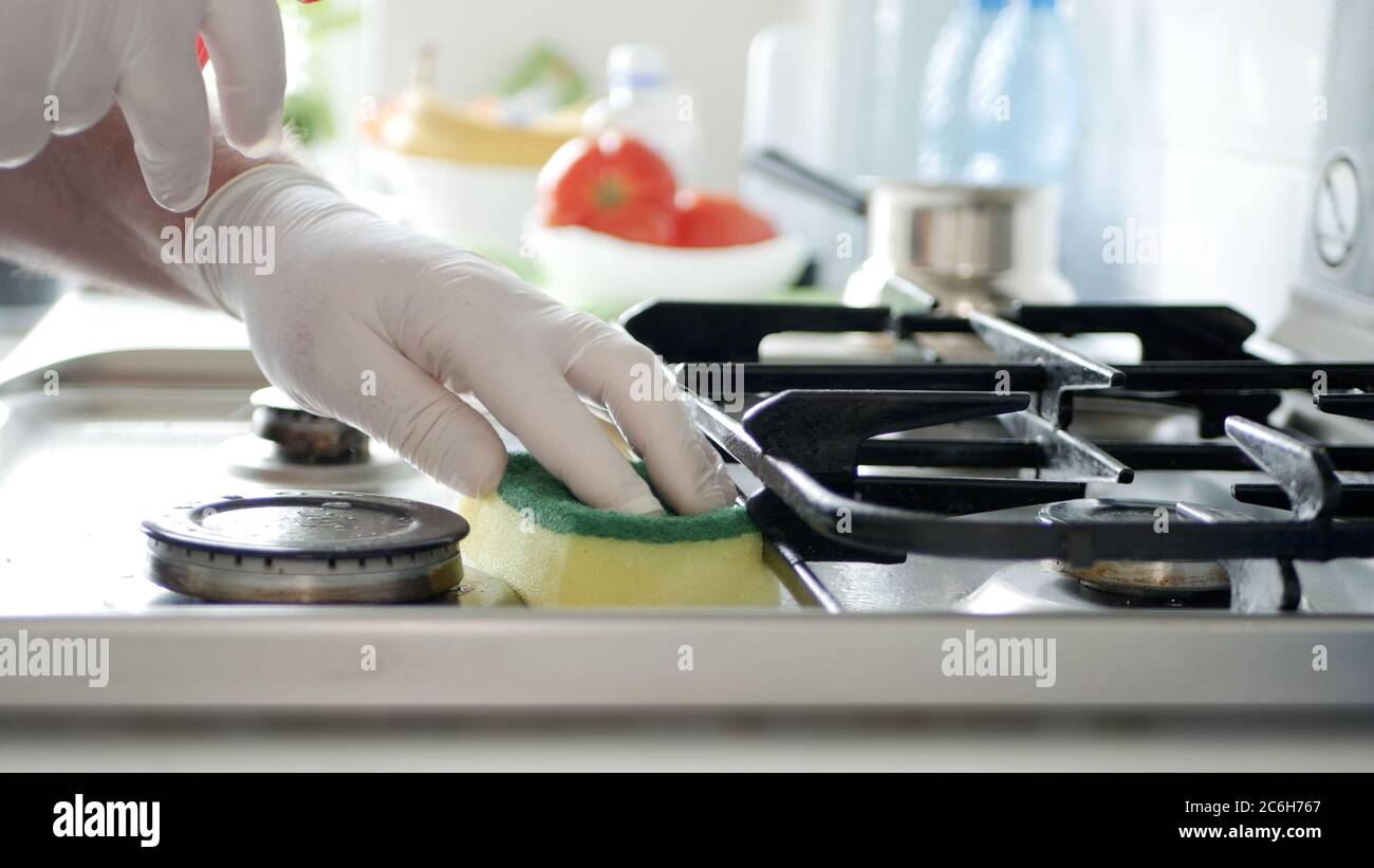 Beschäftigte Person in der Küche tragen Handschuhe reinigt mit Lösung der Herd Herd. Stockfoto