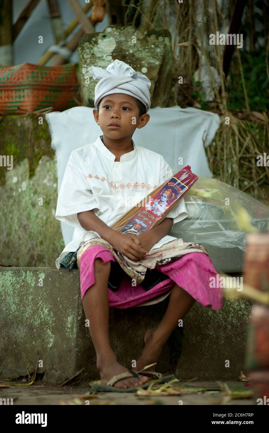 Junge mit Udeng (Kopfbedeckung) und Weihrauch während des Siat Sampian Coconut Leaf war Festivals, Pura Samuan Tiga, Ubud, Bali, Indonesien Stockfoto