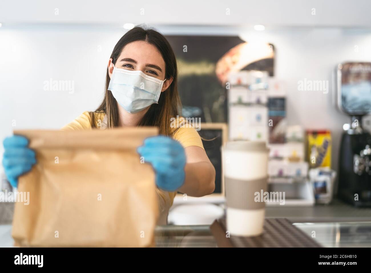 Barbesitzer, der nur mit Bestellungen zum Mitnehmen während des Corona-Virus-Ausbruchs arbeitet - junge Angestellte mit Gesichtsmaske, die Essen zum Mitnehmen gibt Stockfoto