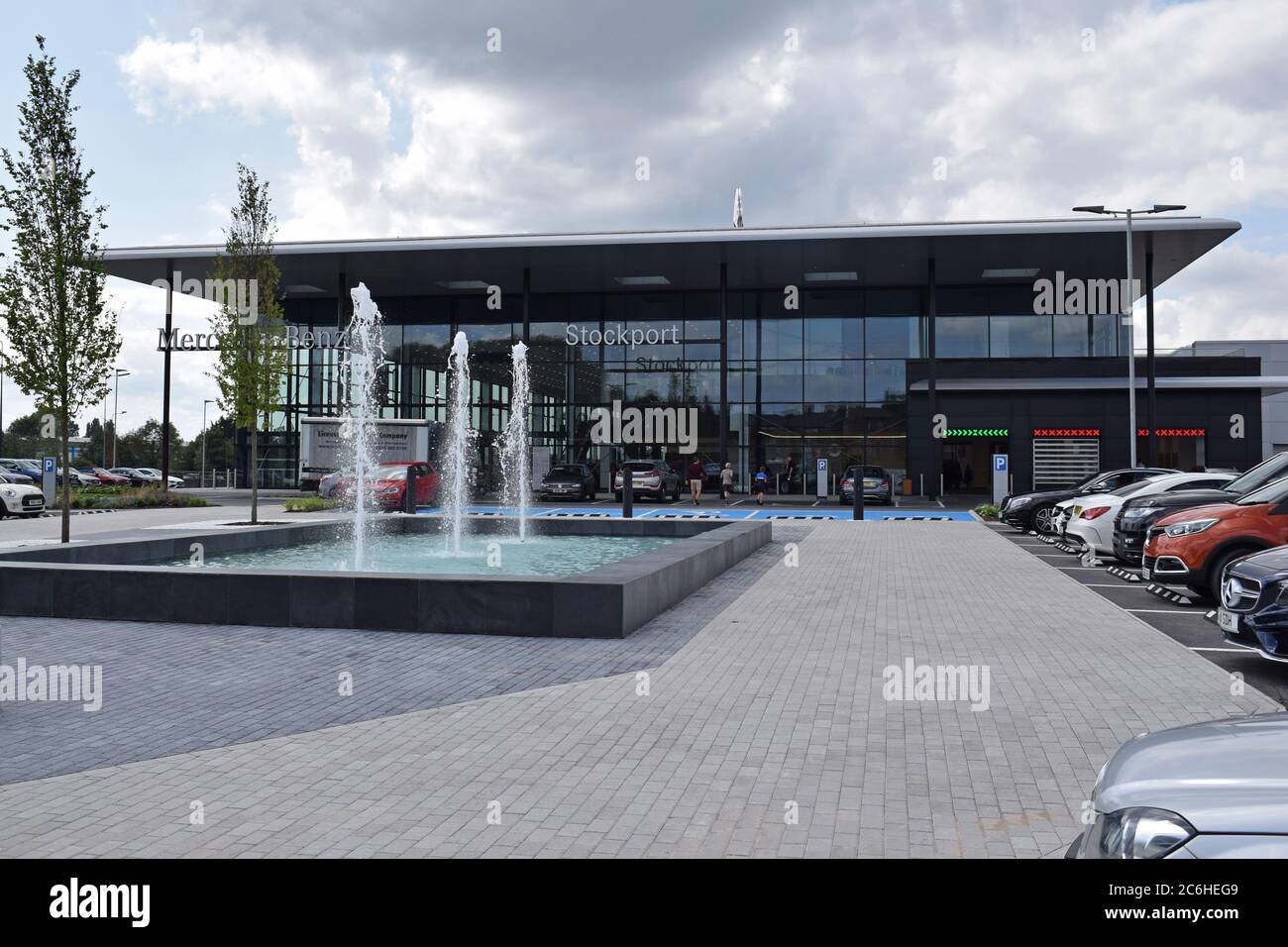Großer Mercedes Benz Autohändler Stockport, Großbritannien eröffnet 29. Juli 2019. Blick auf das Betreten mit Brunnen und geparkten Autos. Stockfoto
