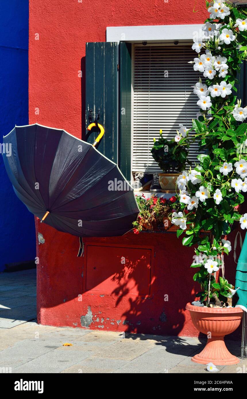 Dekorierte Fassade mit Blumen und offenen Regenschirm von bunten Häusern auf der berühmten Insel Burano, Venedig. Venedig und die venezianische Lagune sind auf der UN Stockfoto