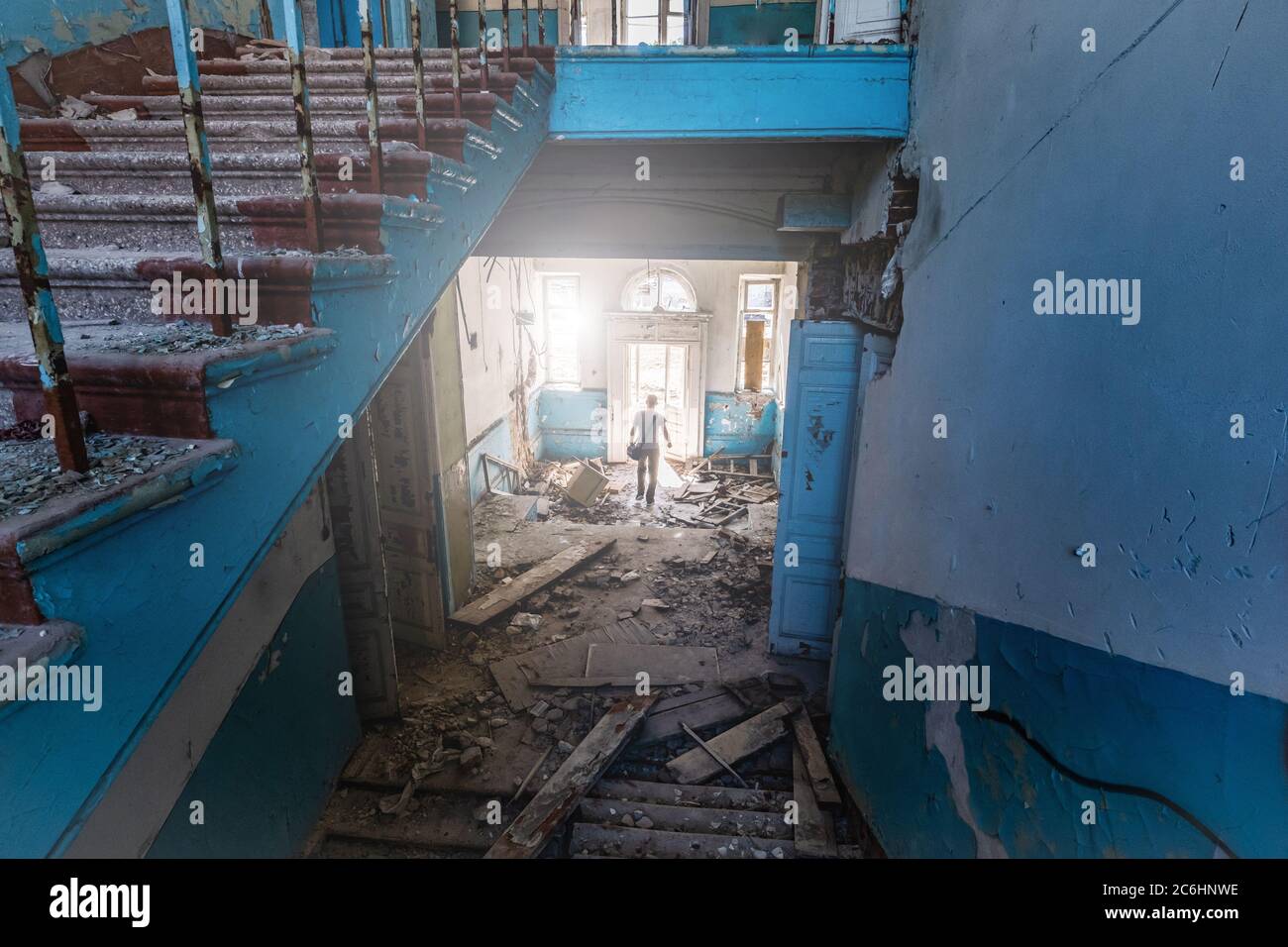 Einsame Person auf dem Hintergrund der kaputten Treppe und Eingang zu verlassenen alten Krankenhaus Stockfoto