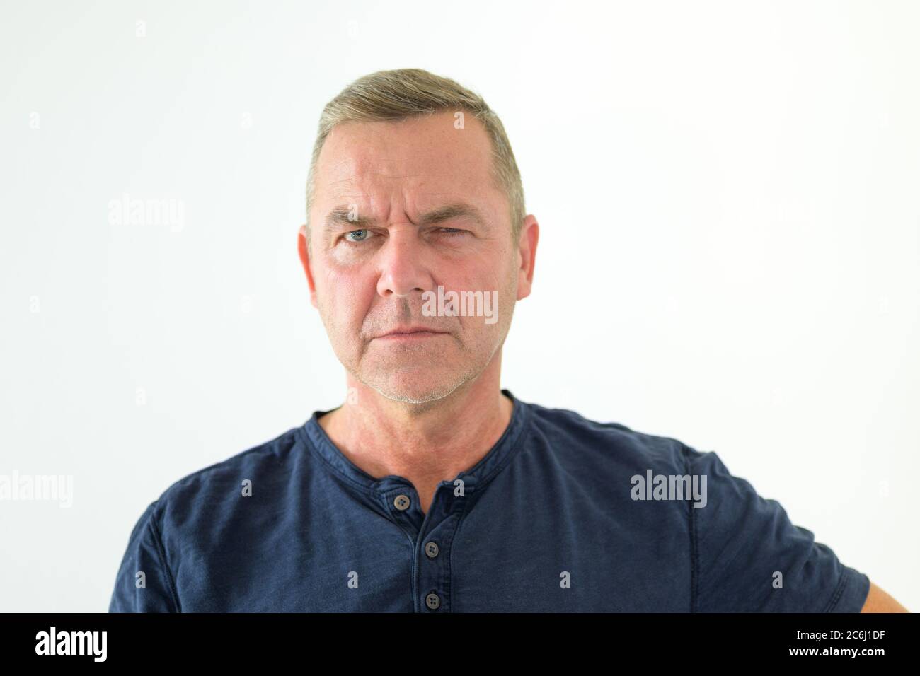 Nachdenklicher Mann, der mit einem ernsten kontemplativen Ausdruck in einem Kopf- und Schulterporträt auf weißem Hintergrund seitlich auf die Kamera blicken kann Stockfoto