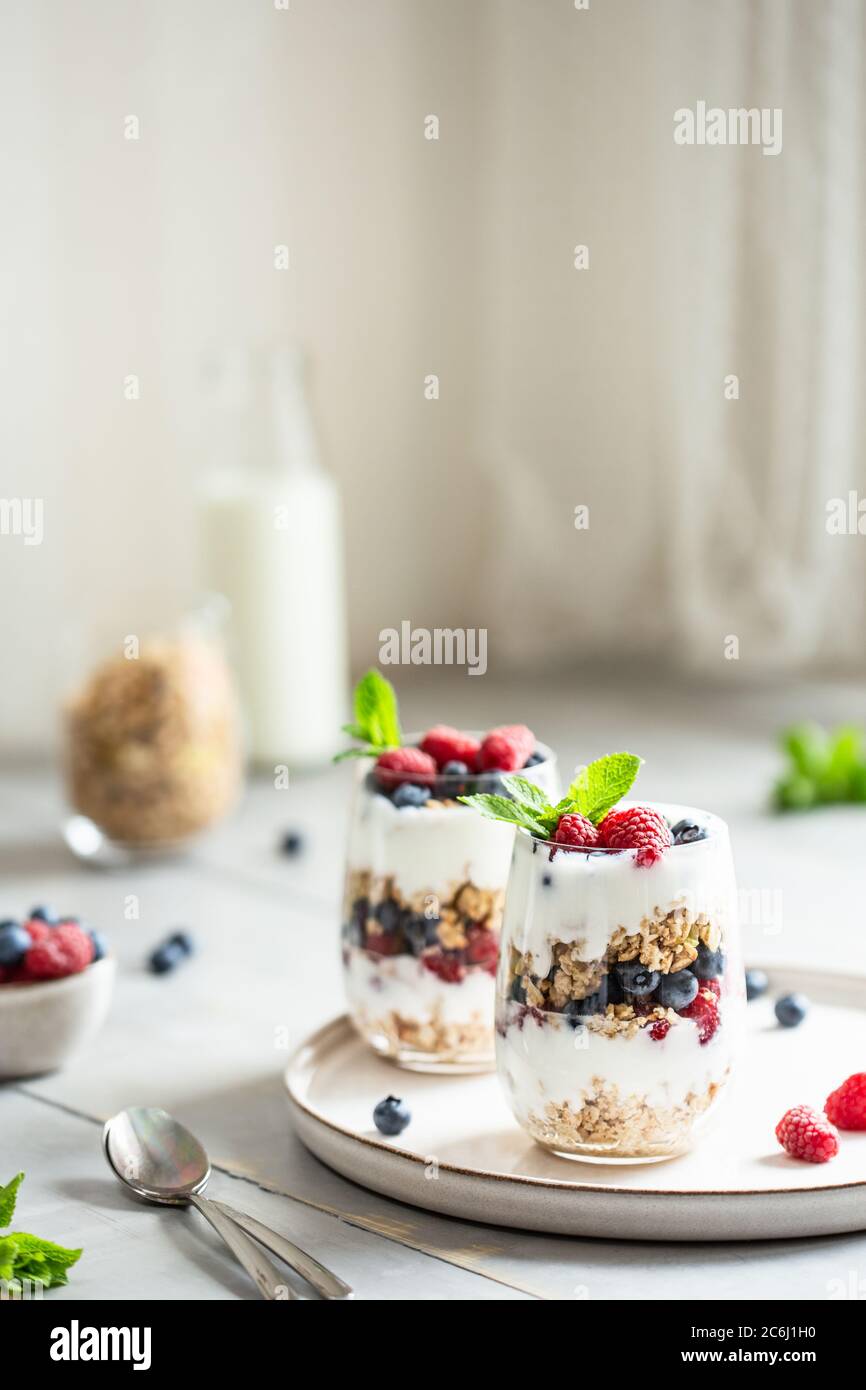 Zwei Gläser Parfait aus Müsli, Beeren und Joghurt auf dem Tisch. Aufnahme im Winkel mit Textort, selektiver Fokus. Stockfoto