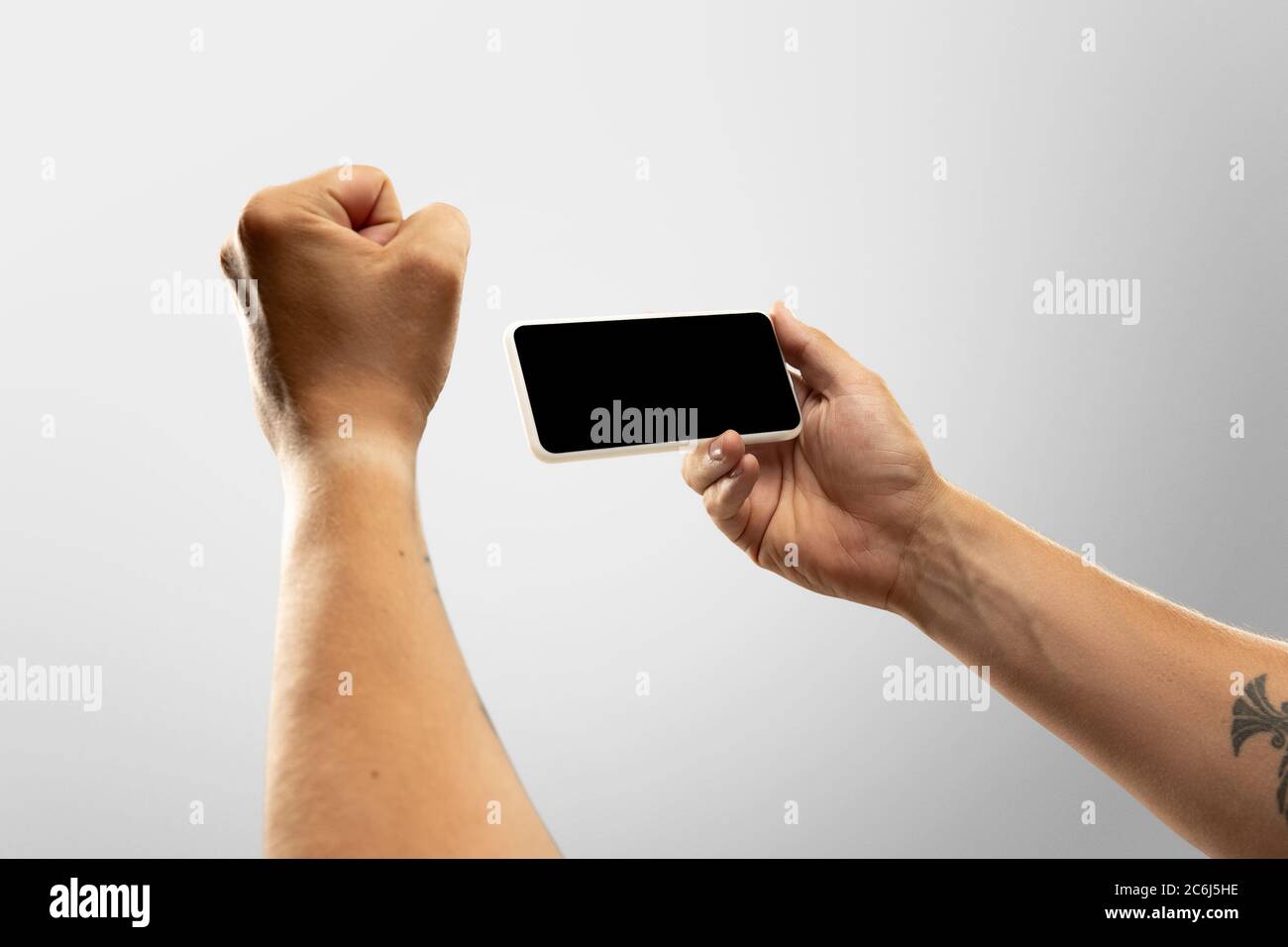 Spannende Momente. Nahaufnahme männliche Hände halten Telefon mit leerem Bildschirm während Online-Wiedergabe von beliebten Sportspielen, Meisterschaften. Copyspace für Werbung. Geräte, Gadgets, Technologien Konzept. Stockfoto