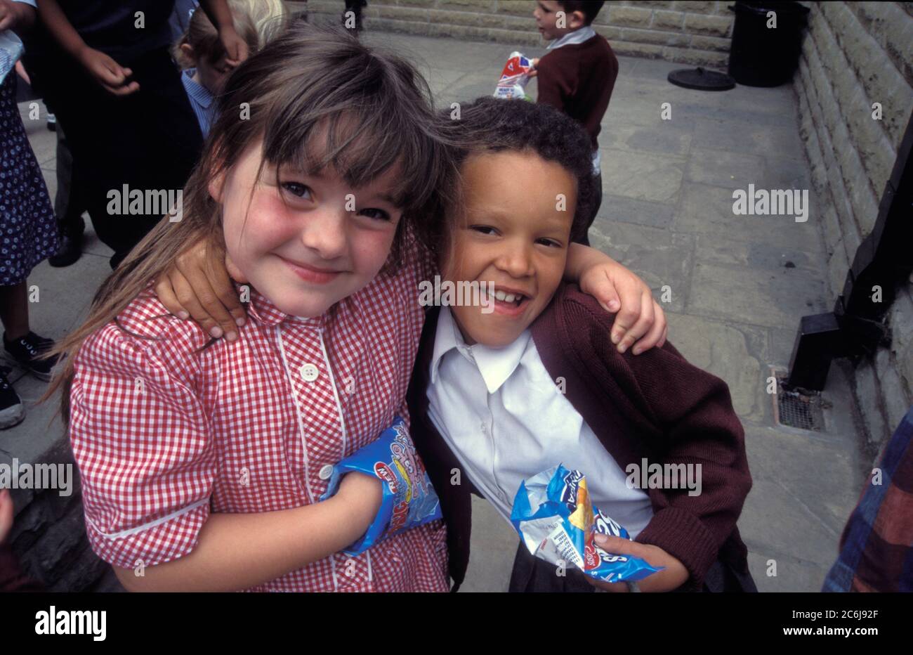 Schülerinnen essen Chips auf Spielplatz; Grundschule; Yorkshire UK Stockfoto